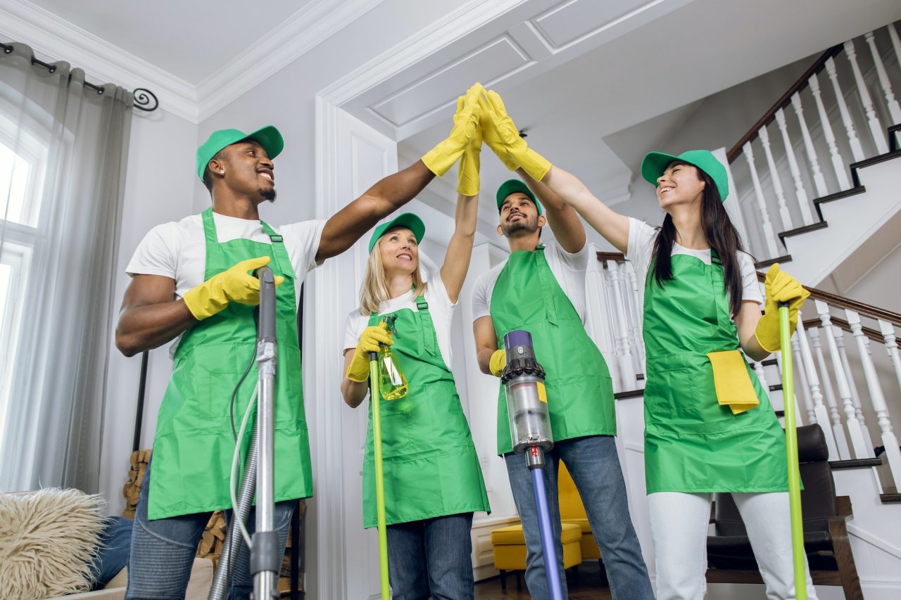 Cheerful multiracial cleaners high-fiving after completing a cleaning task