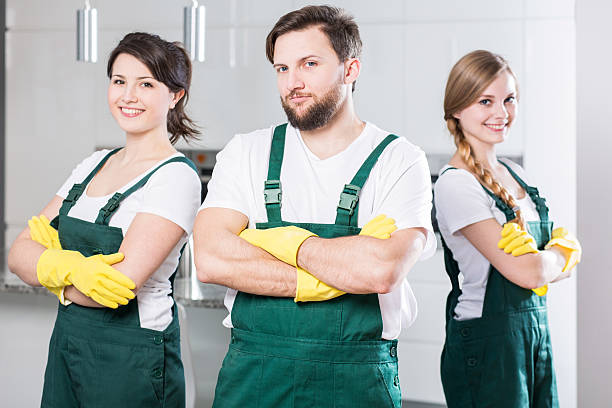 Three young people in cleaning uniforms standing together
